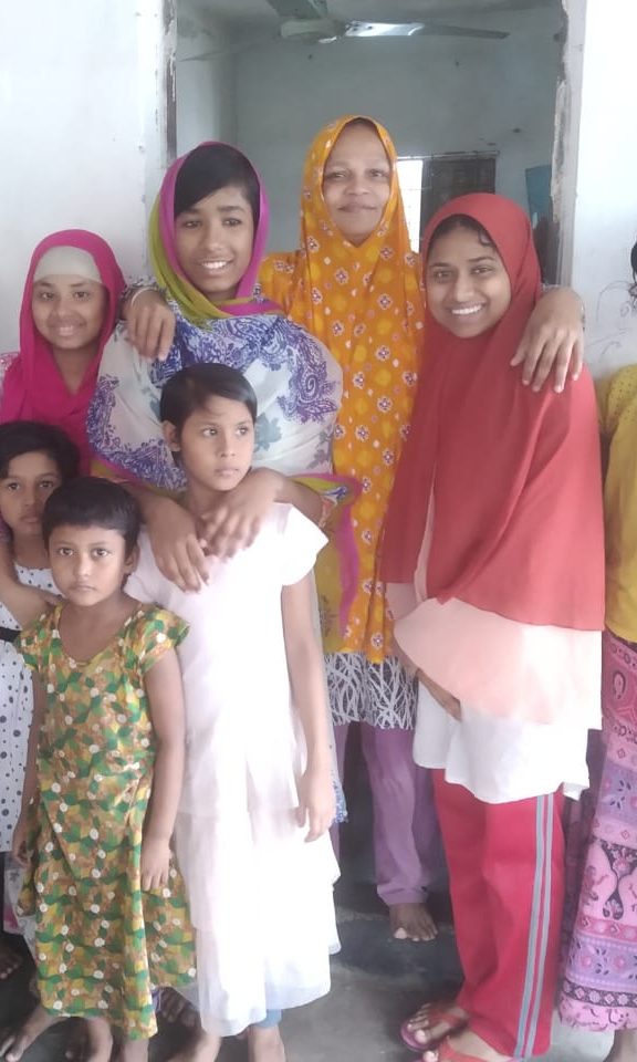 Group photo of Hazera Begum surrounded by the girls she's raising at Hazera's house