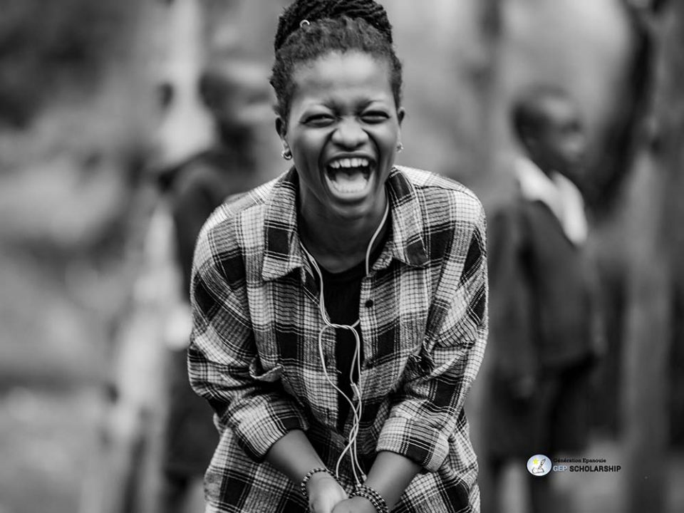A girl in Congo plays a game in the school playground. She has a huge smile in her face. Black and white photo.